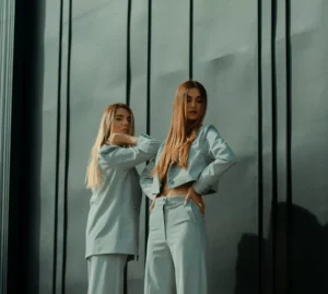 2 women in white long sleeve shirt standing beside glass window